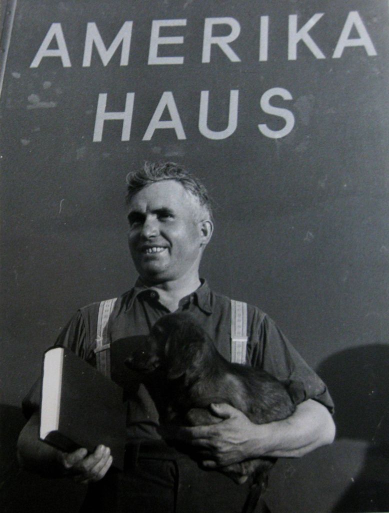 A man holding a dachshund in front of a bookmobile